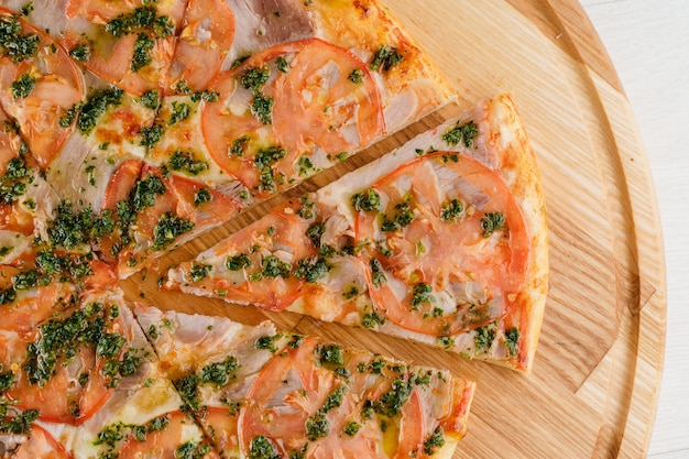 Gros plan de pizza sur une surface en bois blanche. Livraison de nourriture pour les personnes qui restent à la maison