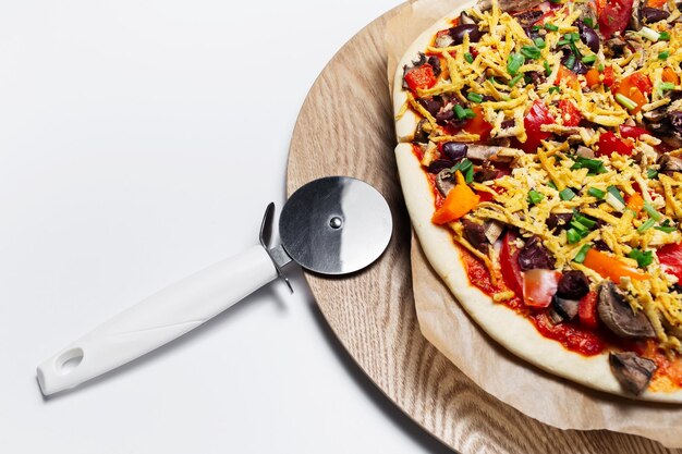 Gros plan de pizza végétalienne maison et couteau sur table en bois et fond blanc