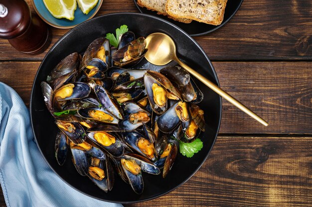 Gros plan d'une plaque avec des moules cuites à la vapeur sur fond de bois foncé