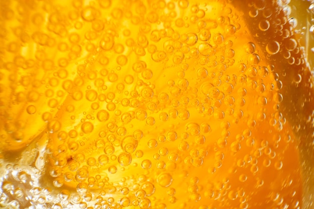 Gros plan plein cadre de tranche d'orange ronde en verre avec gin alcoolisé rafraîchissant transparent et cocktail tonique avec de petites bulles