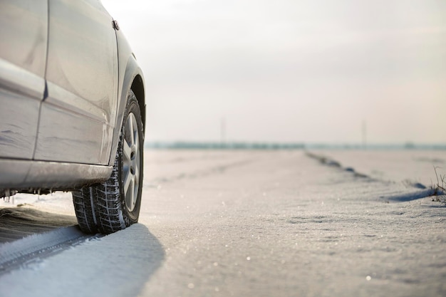 Gros plan d'un pneu de voiture garé sur une route enneigée le jour de l'hiver Concept de transport et de sécurité