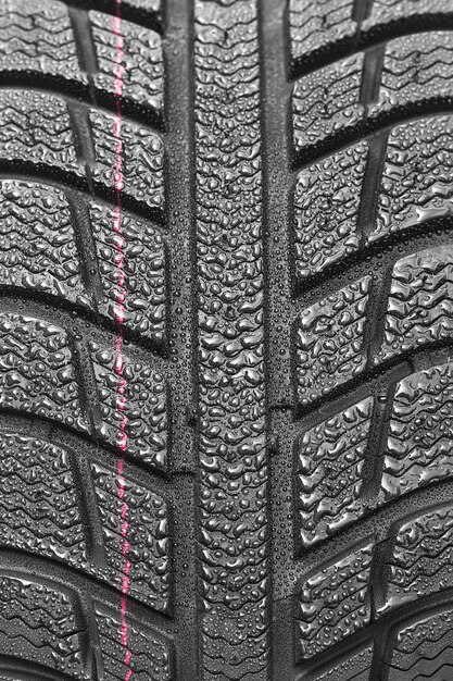 Photo gros plan sur les pneus de voiture structure de profil de roue d'hiver avec des gouttes d'eau sur fond blanc