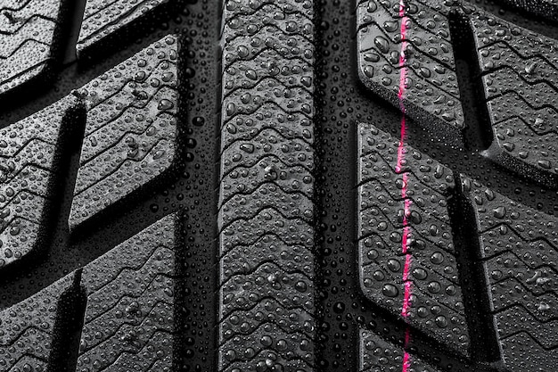 Gros plan sur les pneus de voiture structure de profil de roue d'hiver avec des gouttes d'eau