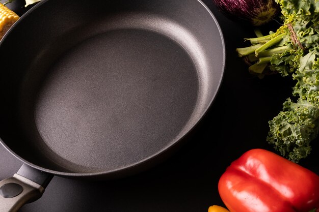 Photo gros plan d'une poêle à frire noire vide par chou frisé et poivron rouge sur la table. aliments sains, légumes, aliments crus, variation et concept biologique.