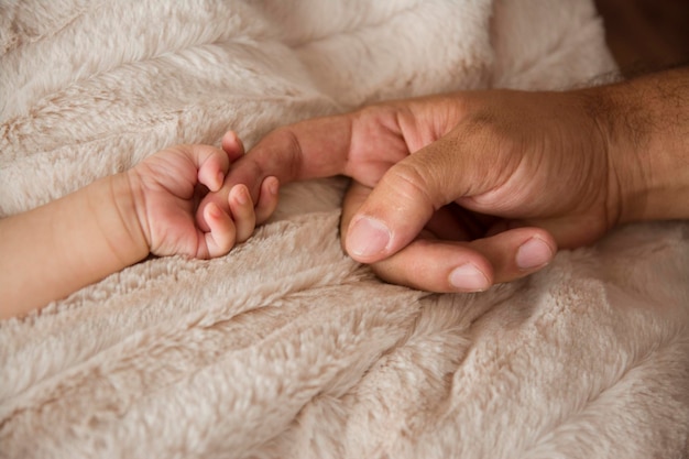 Photo gros plan d'une poignée de main entre un nouveau-né et son père