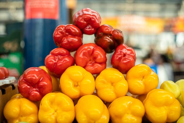 Gros plan de poivrons rouges et jaunes frais arrangés au marché. Arrière-plan flou. Concept d'alimentation saine.