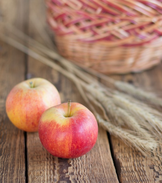 Gros Plan Pommes Rouges, épis De Blé Et Panier En Osier Sur Fond En Bois. Faible Profondeur De Champ.