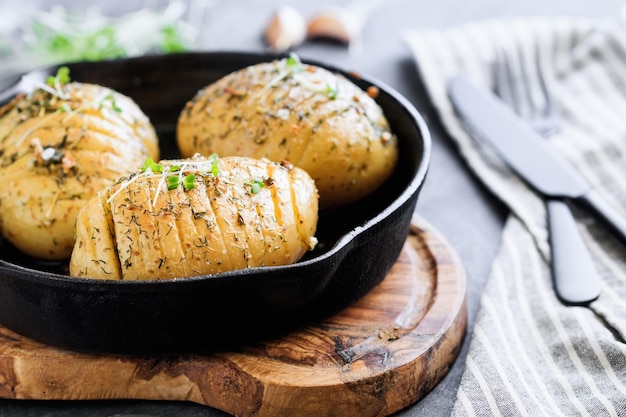 Gros plan de pommes de terre au four faites maison avec de l'huile d'olive, de l'ail, de la moutarde, du romarin, de l'aneth et du poivre noir dans une poêle à frire