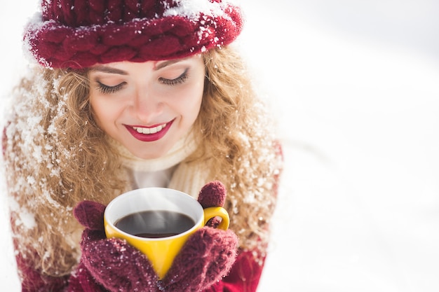 Gros plan le portrait de la belle jeune femme avec une tasse de café chaud