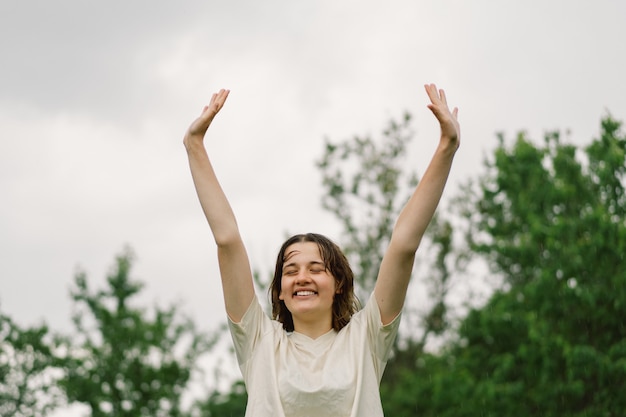 Gros Plan Portrait De Fille Adolescente. Joyeuse adolescente joyeuse avec un visage prononcé à partir de petites éclaboussures d'eau pulvérisées ou d'une pluie d'été chaude à l'extérieur.