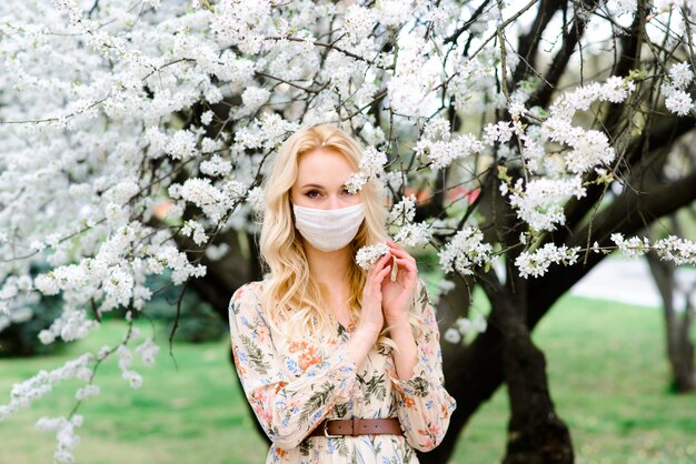 Gros plan le portrait d'une fille tendre dans un chemisier blanc sous un cerisier en fleurs