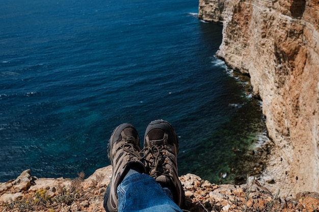 Gros plan POV de chaussures de randonnée d'un voyageur indépendant au sommet d'une montagne en regardant la vue