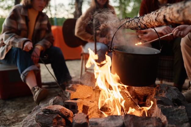 Gros plan de la préparation des aliments dans une casserole sur un feu avec des gens assis en arrière-plan