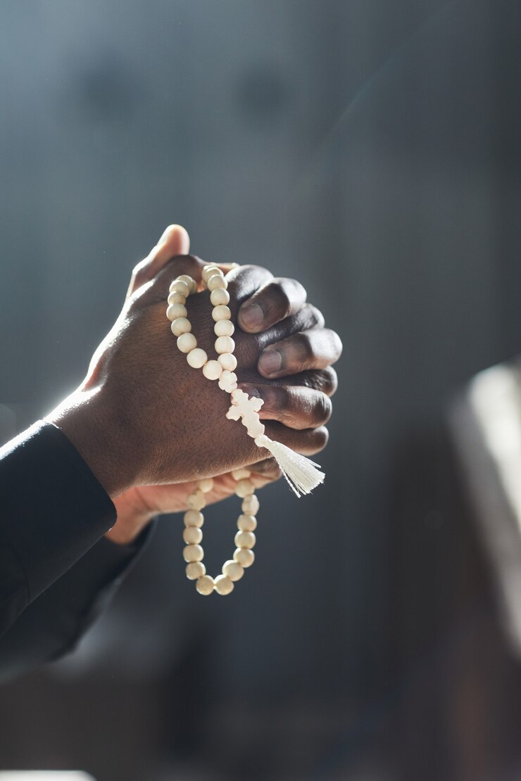 Photo gros plan sur un prêtre africain tenant un chapelet et priant