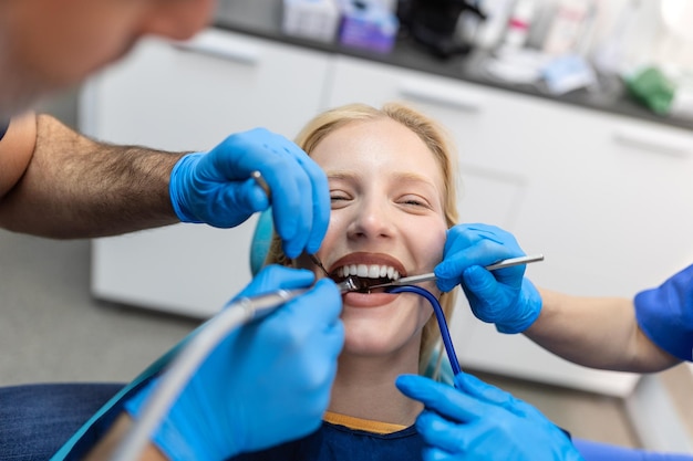 Gros plan d'une procédure de forage dentaire chez un dentiste s'approchant d'un patient avec des instruments dentaires tenus dans les mains protégées par des gants chirurgicaux