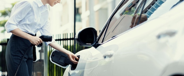 Gros plan progressiste femme parlant au téléphone s'appuyant sur un véhicule électrique