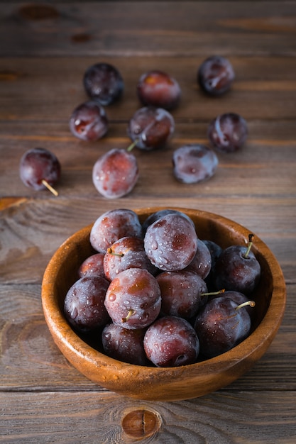 Gros plan sur les prunes bleues mûres dans un bol en bois