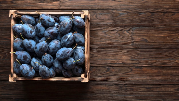 Gros plan de prunes mûres dans une caisse en bois. vue de dessus