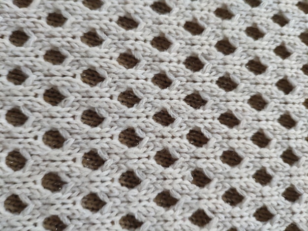 Un gros plan d'un pull en tricot blanc avec un motif marron