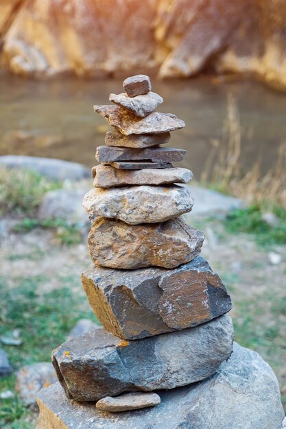 Gros plan d'une pyramide de pierres sur le fond de la rivière et des rochers.