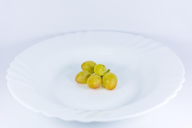 Gros plan d'un raisin blanc sur la plaque blanche