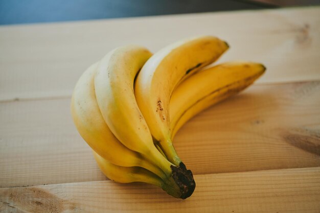Gros plan d'un régime de bananes sur un fond de table de cuisine en bois