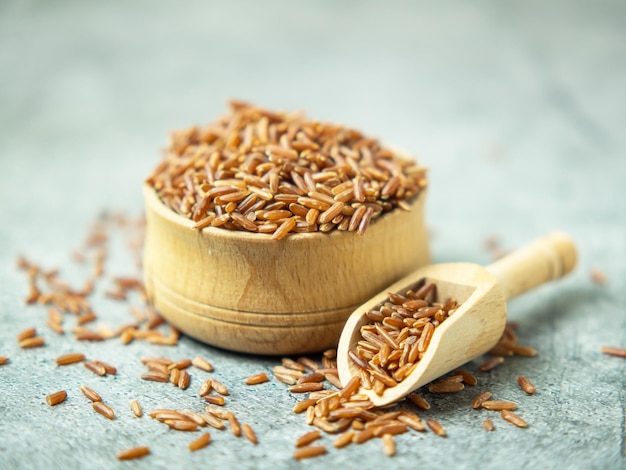 Gros plan de riz brun dans un bol en bois et scoop