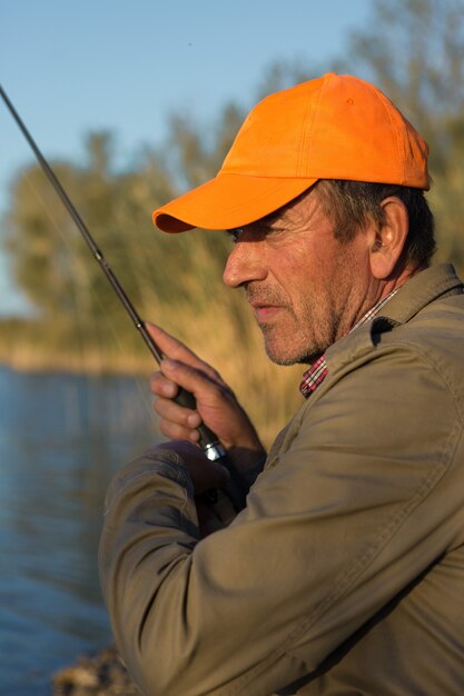 Photo gros plan de roue de canne à pêche, homme pêchant avec un beau coucher de soleil.