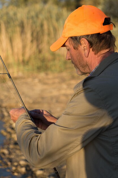 Photo gros plan de roue de canne à pêche, homme pêchant avec un beau coucher de soleil.