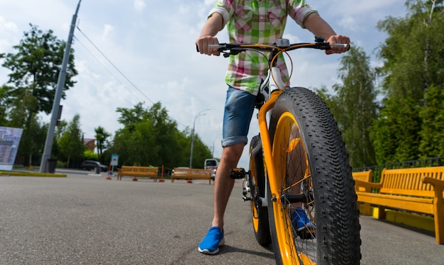 Gros plan d'une roue de vélo avec un jeune homme à travers le parc