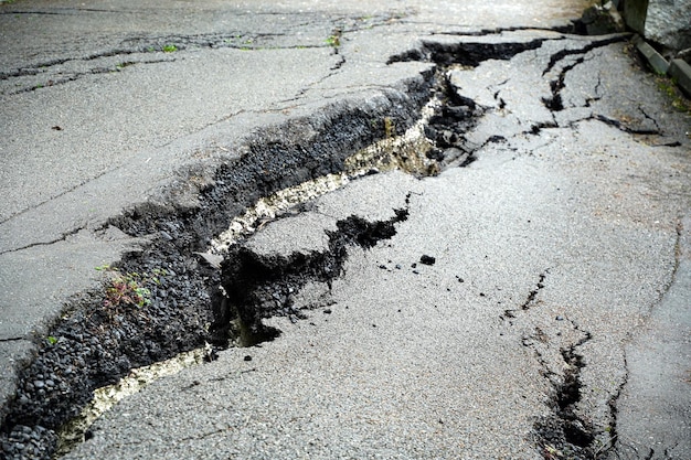 Gros plan sur une route asphaltée fissurée et cassée par un tremblement de terre