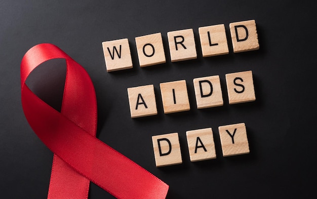 Gros plan ruban rouge VIH ruban de sensibilisation à la journée mondiale du sida et le texte sur fond rouge Concept de soins de santé et de médecine