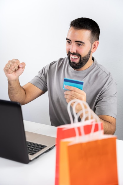 Gros plan de sacs colorés et homme d'arrière-plan excité par l'ordinateur et tenant la carte pour le concept de magasinage en ligne shopping vendredi noir cyber lundi ventes noël