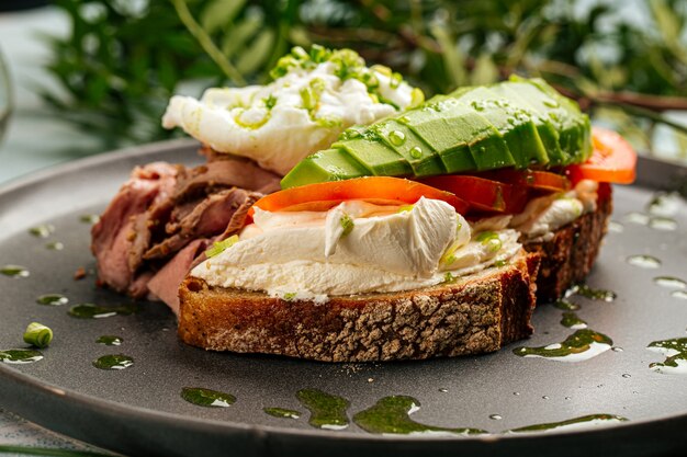 Gros plan sur sandwich à l'avocat avec rosbif et œuf poché pour le petit déjeuner