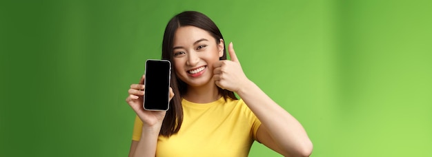 Gros plan satisfait jolie fille asiatique donner des commentaires positifs pouce montrant l'écran du smartphone introduire