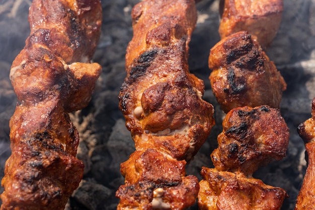 Gros plan de shish kebab de porc grillé savoureux sur des brochettes de cuisson au charbon de bois