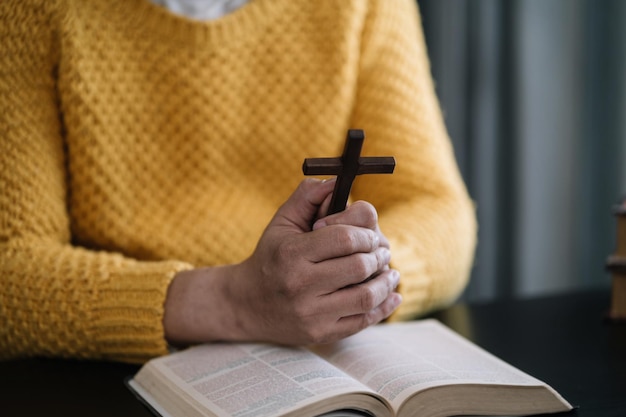 Gros plan d'une simple croix chrétienne en bois sur la Bible Concept d'espoir foi christianisme religion