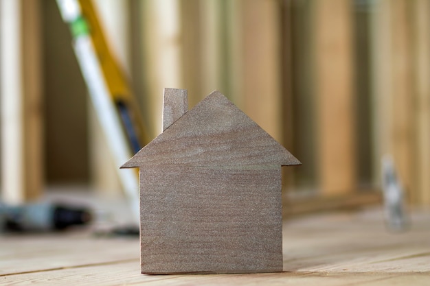 Gros plan d'une simple petite maison modèle brune sur des outils de construction floue. Construction, construction et investissements dans l'immobilier, la propriété et la propriété du concept de maison de rêve.