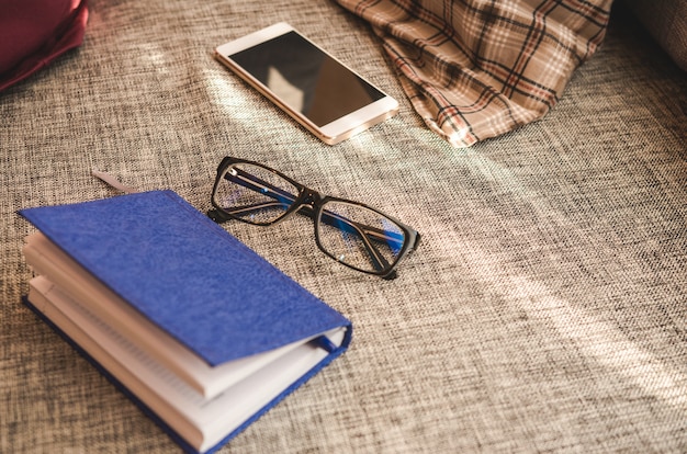 Gros plan, smartphone, planification, livre, lunettes, sofa