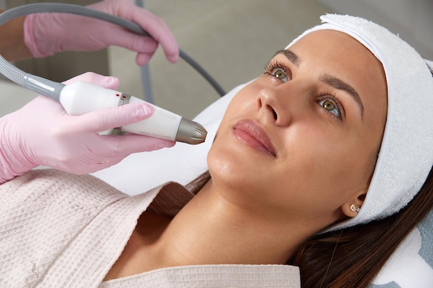 Gros plan sur les soins de la peau du visage d'une femme recevant un traitement d'épluchage par microdermabrasion faciale chez un cosmétique