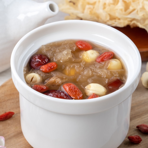 Gros plan de la soupe aux champignons blanche-neige sucrée traditionnelle chinoise avec graines de lotus, dattes rouges (jujube) et goji (goji, gojiberry).