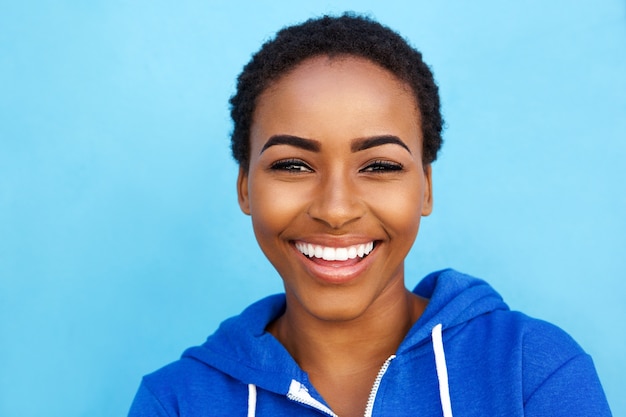 Gros plan souriant jeune femme noire sur fond bleu