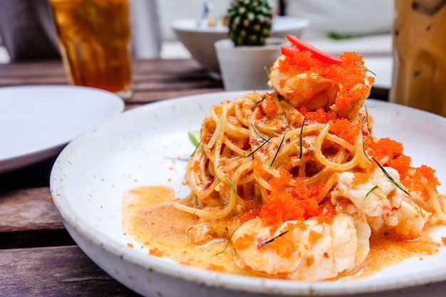 Gros plan de spaghetti aux crevettes en plaque blanche sur la table à manger en bois au restaurant