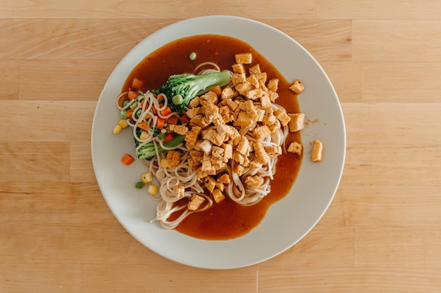 Gros plan de spaghettis de poulet faits maison servis sur un plat blanc.