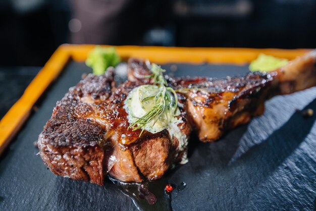 Gros plan sur un steak juteux magnifiquement grillé avec du beurre et des assaisonnements. Viande grillée dans un restaurant.