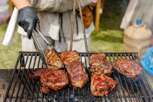 Gros plan de steaks de viande sur le gril et barbecue avec des légumes cornthe chef tient la viande sur