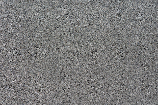 Gros plan sur la surface de sable volcanique de couleur noire. Fond de nature détaillée ou texture de motif prise dans un environnement naturel. Altéré de nombreuses années, effet unique et inimitable au design texturé