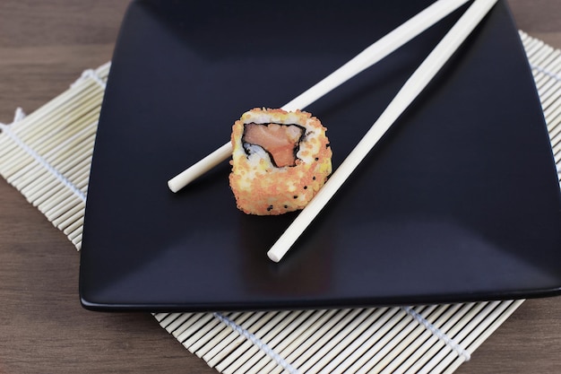 Gros plan de sushis et de baguettes sur une table en bois