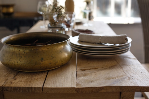 Photo gros plan d'une table en bois avec des assiettes en porcelaine et un plat en cuivre