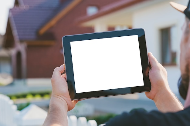 Gros Plan D'une Tablette Dans Les Mains D'un Homme, Sur Le Fond De La Maison.